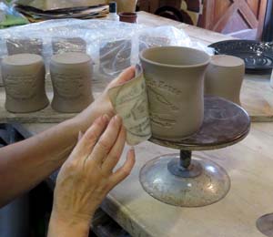 A polymer die impresses a design on a mug at Elk Falls Pottery